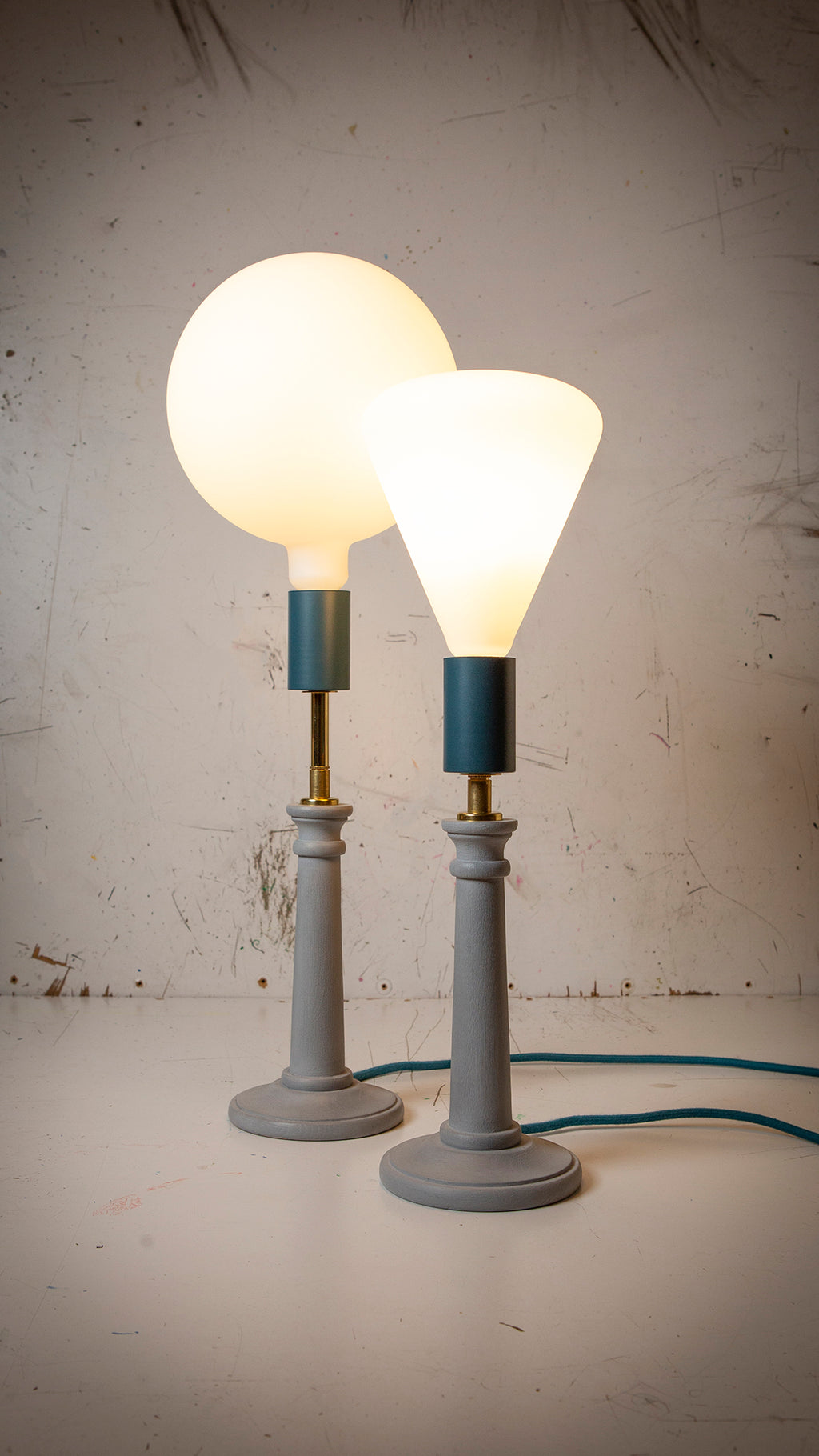 two blue candlestick lamps with large cone and circular porcelain bulbs