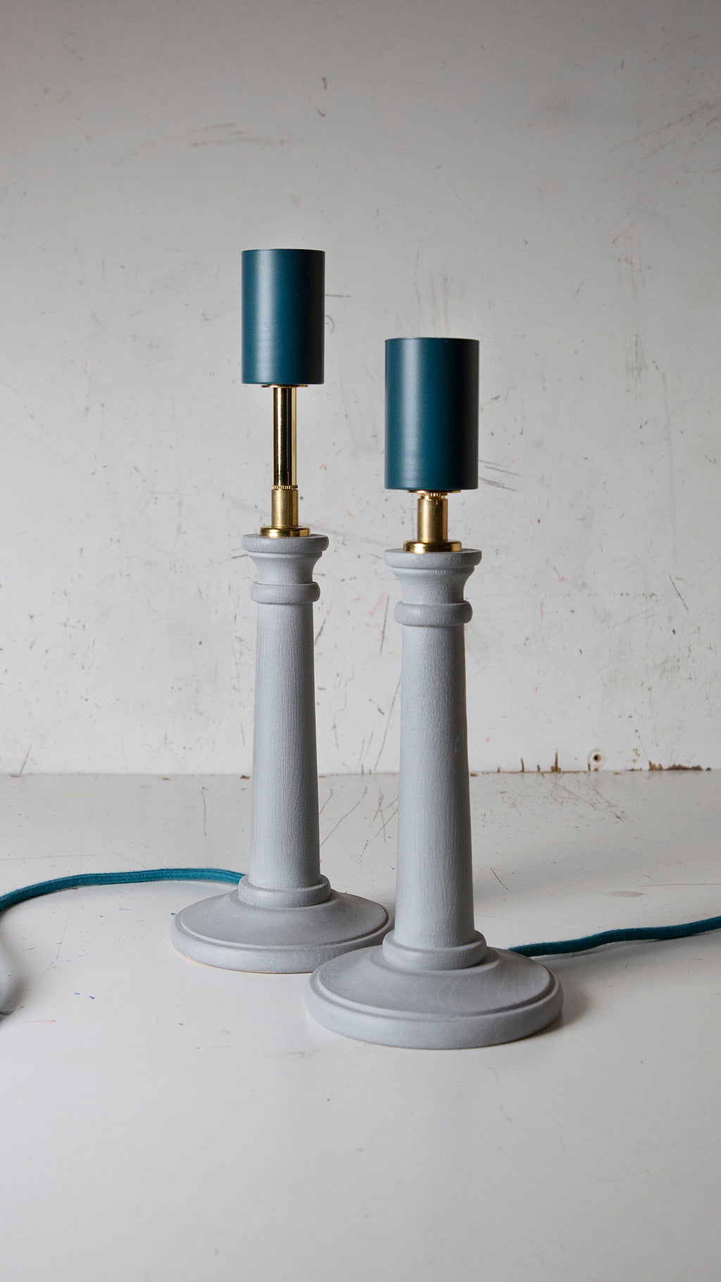 Two light blue Candlestick lamps with teal lamp holder and cord with brass details
