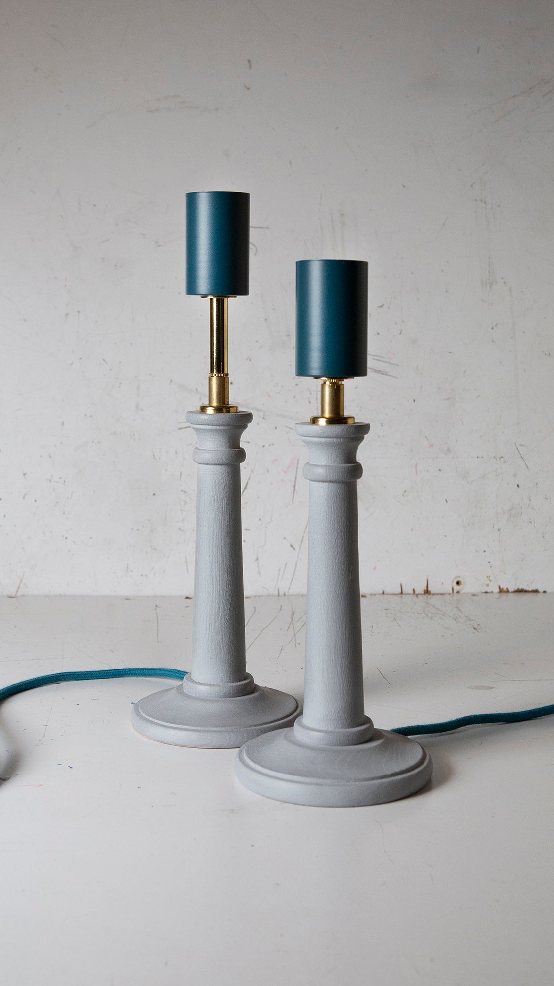 Two light blue Candlestick lamps with teal lamp holder and cord with brass details