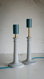 Two table lamps with light blue pastel bases and teal lamp holders on a white surface.