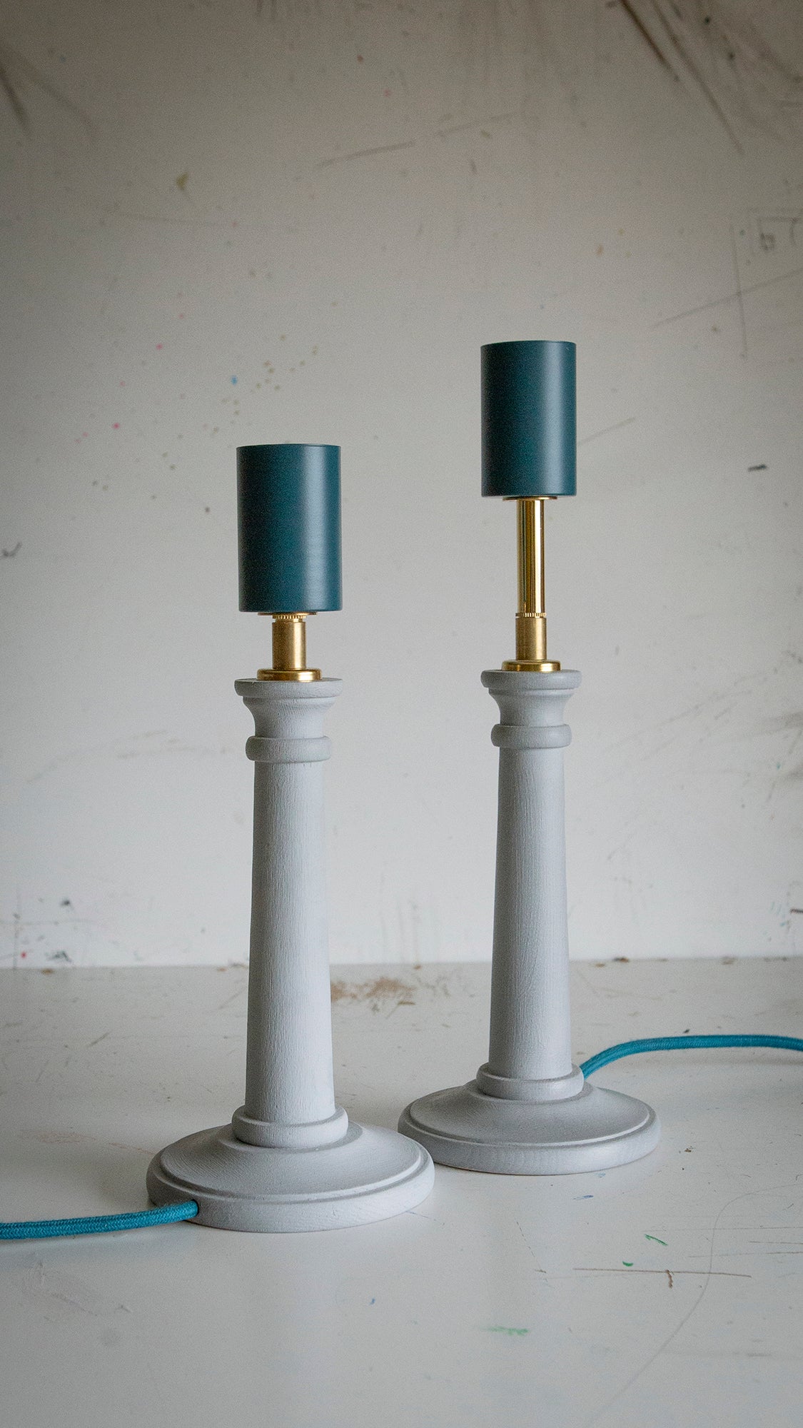 Two table lamps with light blue pastel bases and teal lamp holders on a white surface.