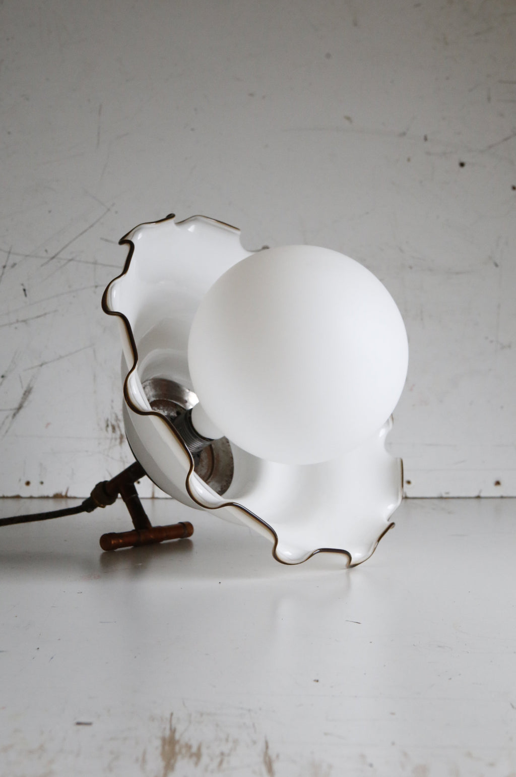 Vintage-style lamp with scalloped edge design on a white surface.