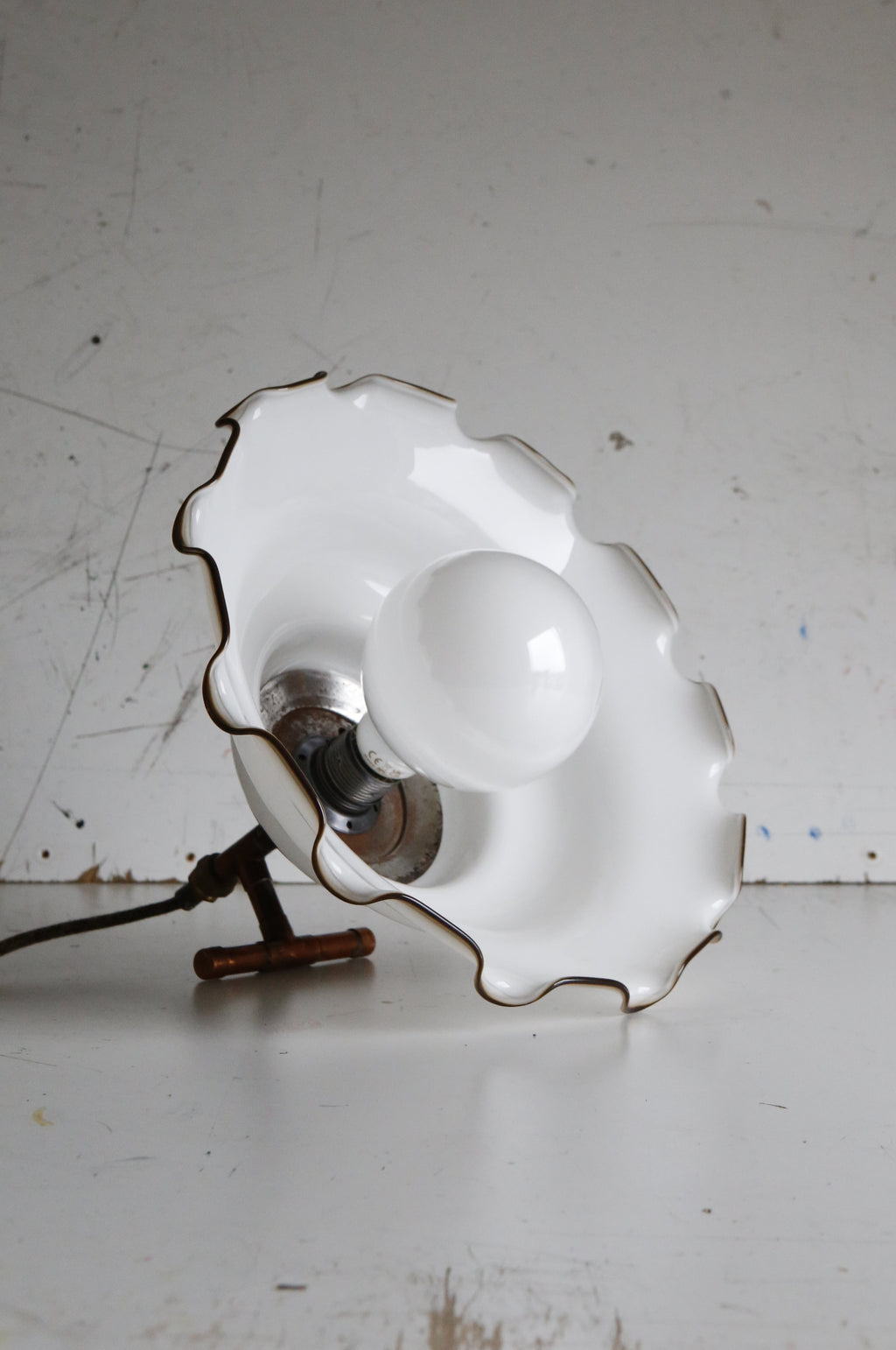 Vintage-style wall lamp with scalloped white shade on a white background