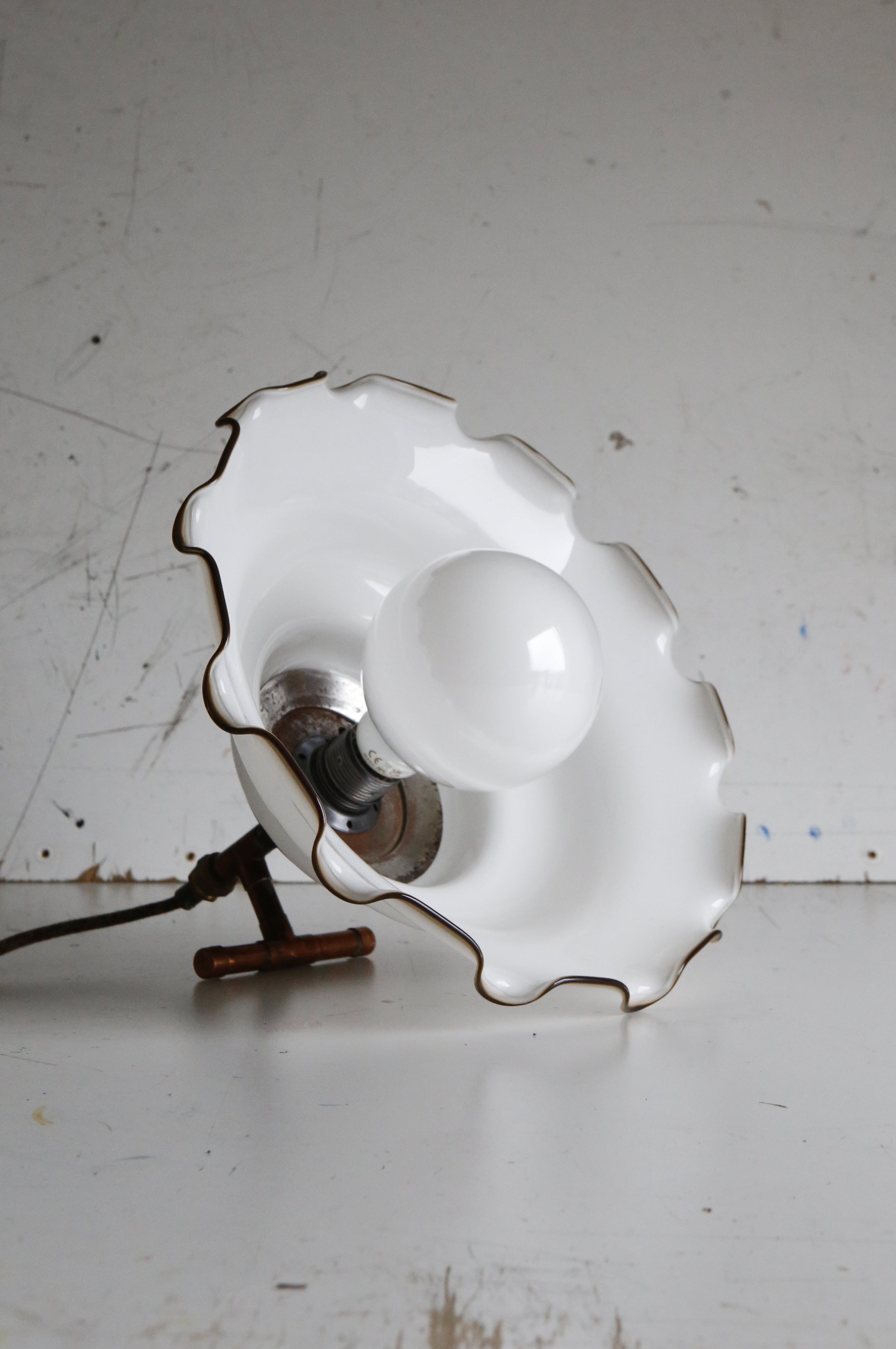 Vintage-style wall lamp with scalloped white shade on a white background