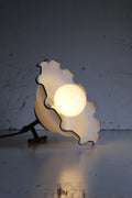 Decorative lamp with wavy design and bulb on a textured surface