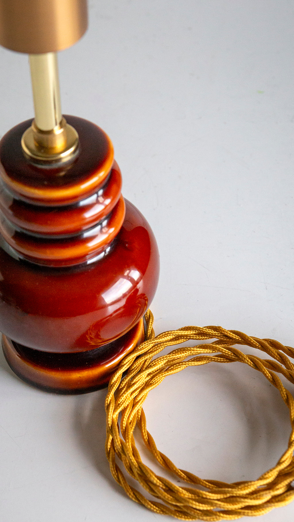 Decorative lamp with a coiled gold cord on a light gray background