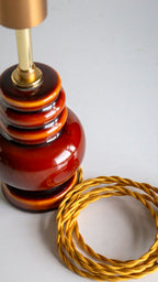 Decorative lamp with a coiled gold cord on a light gray background