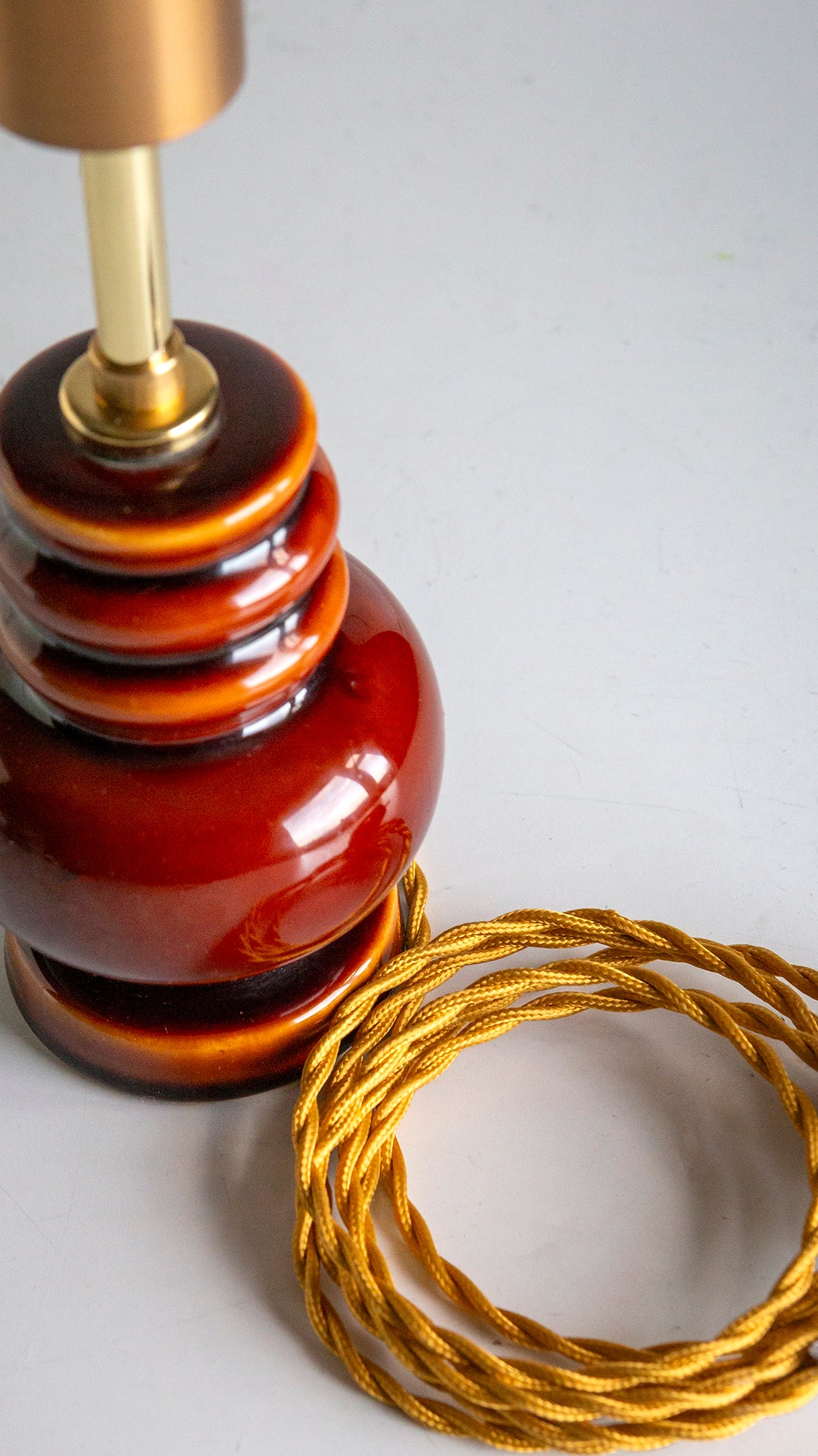 Decorative lamp with a coiled gold cord on a light gray background
