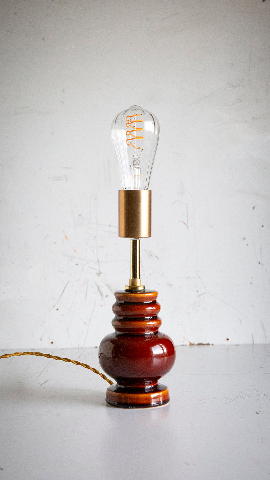 Vintage-style table lamp with a brown base and gold accent on a white surface.