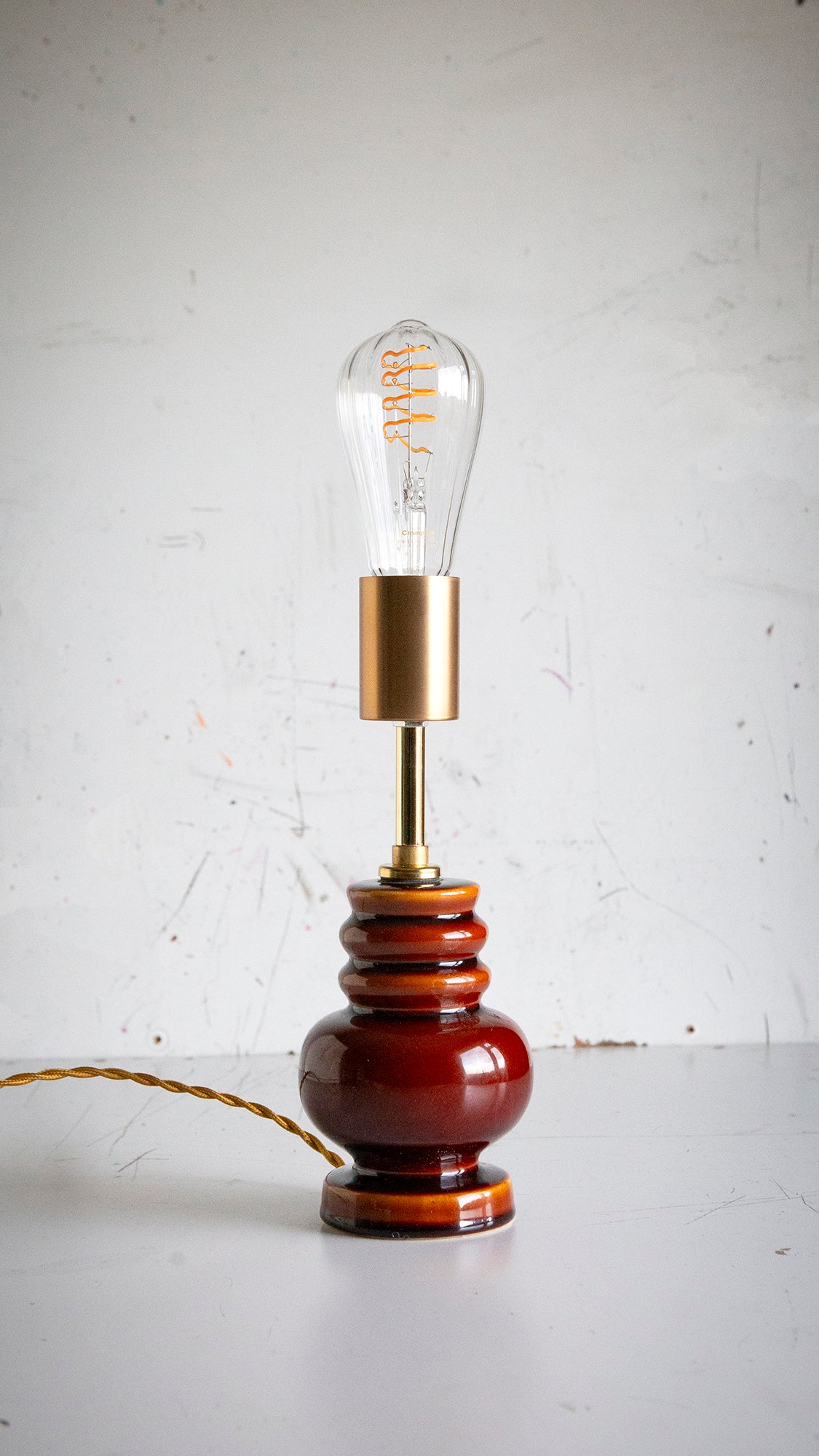 Vintage-style table lamp with a brown base and gold accent on a white surface.