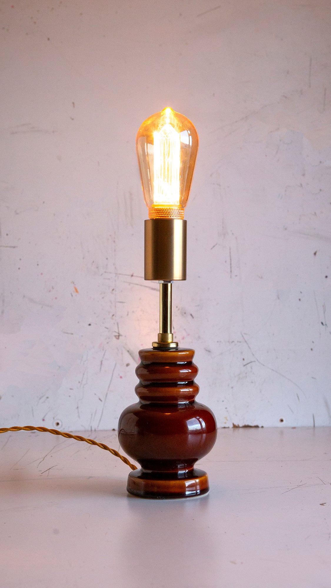Vintage-style table lamp with brown ceramic base and brass fittings on a white surface.