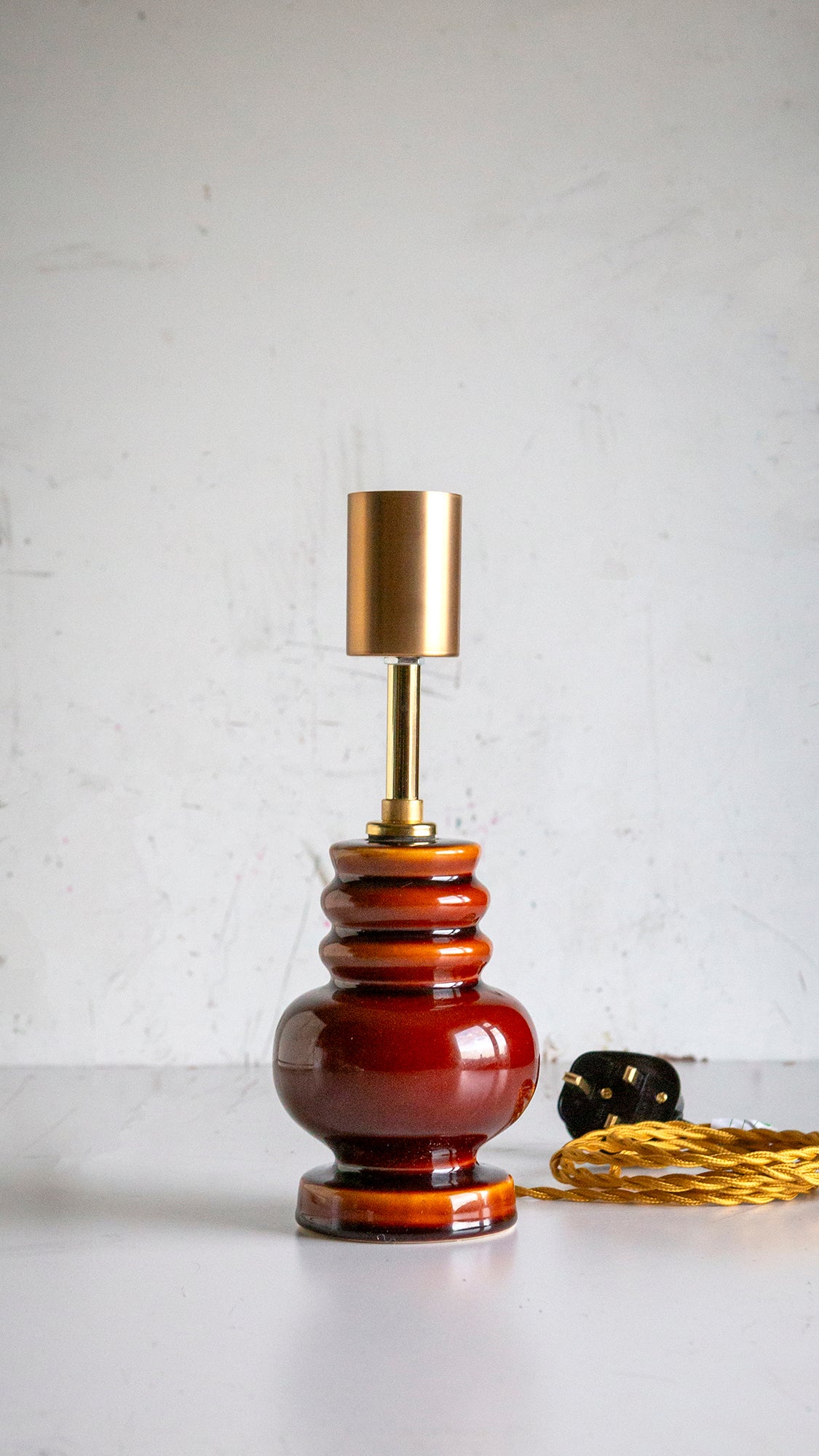 Decorative lamp with a brown ceramic base and gold fitting on a white surface.