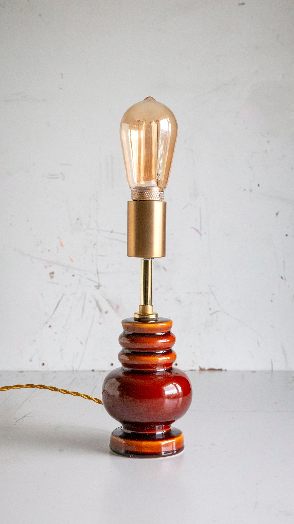 Vintage-style lamp with a brown base and gold bulb holder on a white surface.