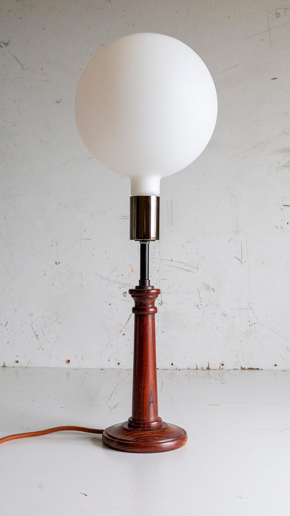 Table lamp with wooden base and white porcelain globe bulb on a light background