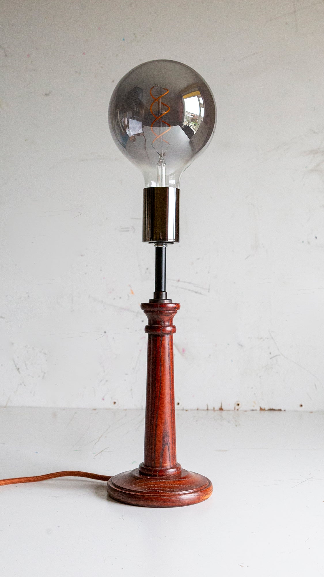 Vintage-style table lamp with wooden base and large smokey bulb on a white background