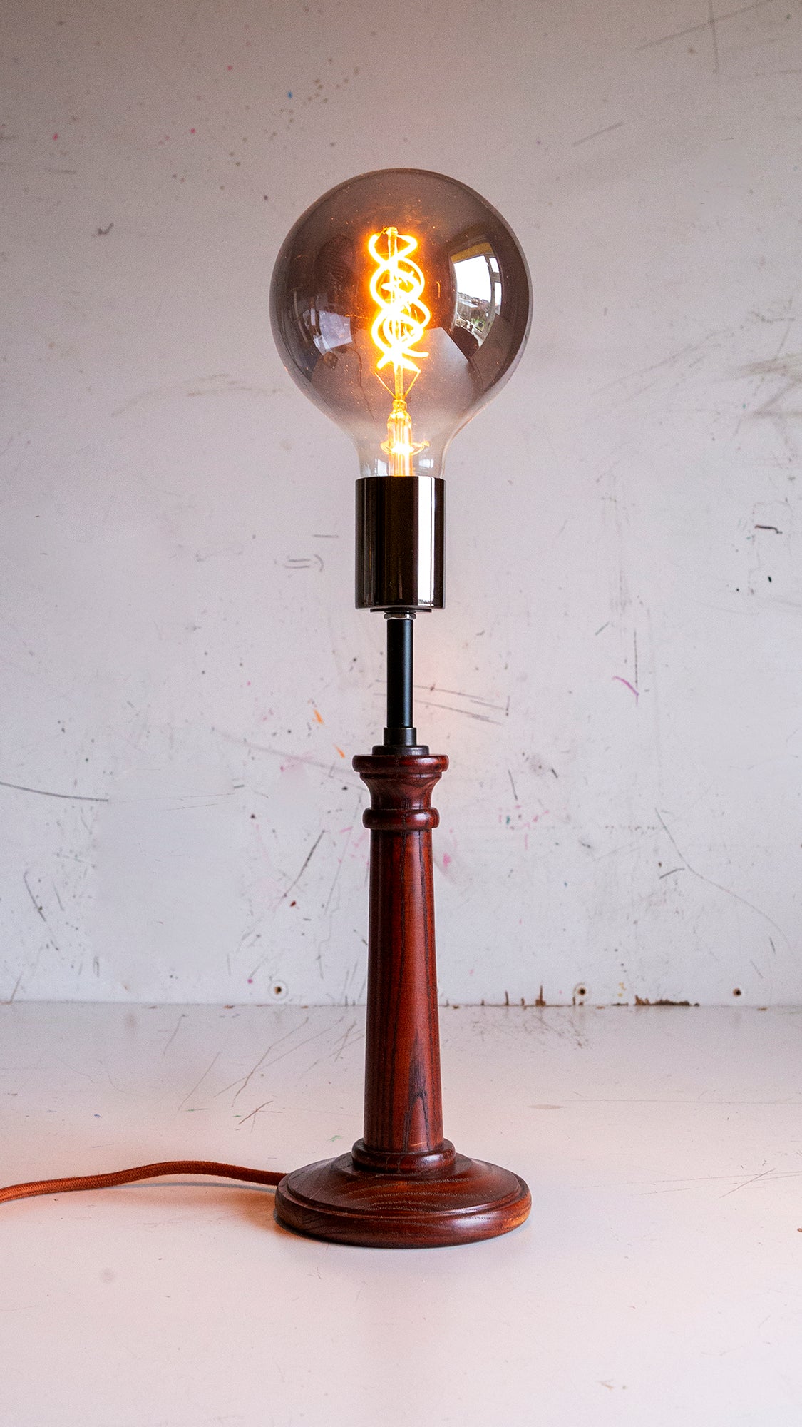Vintage-style bhs 1980s table lamp with a wooden base and smokey bulb on a white background
