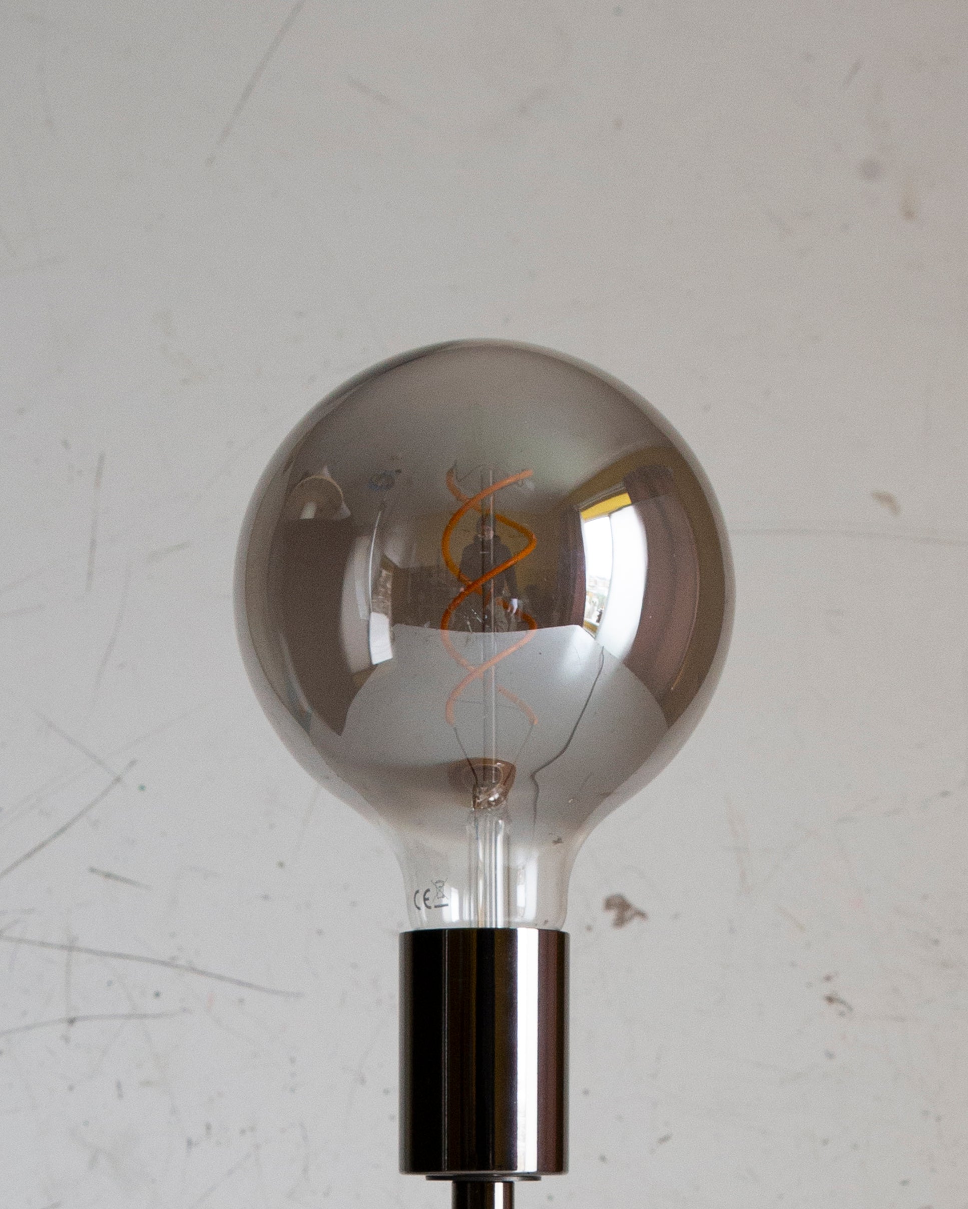 Silver or grey smokey spherical light bulb on a white background