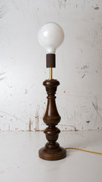 Vintage-style table lamp with wooden base and white bulb on a white background