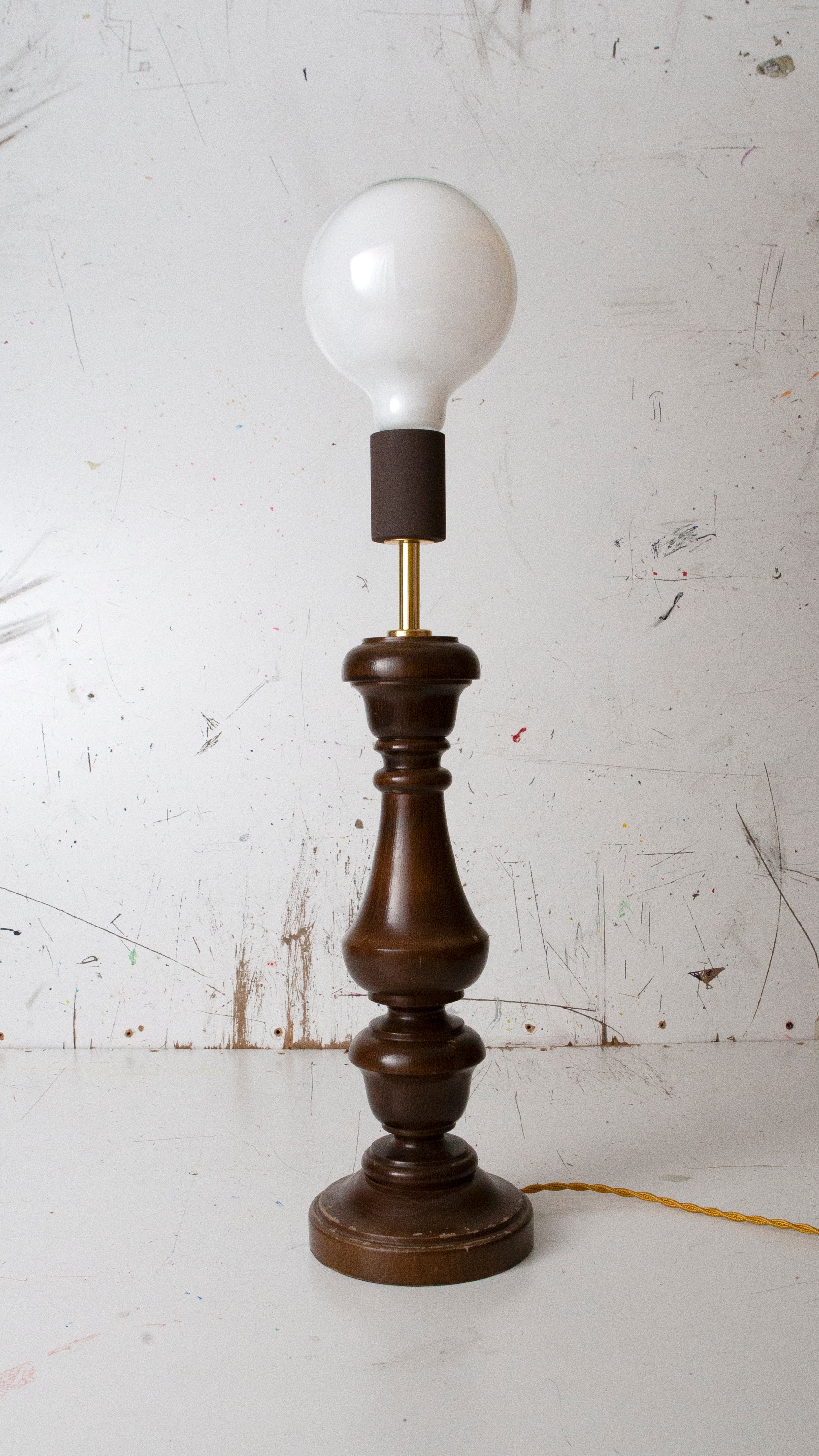 Vintage-style table lamp with wooden base and white bulb on a white background