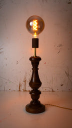 Vintage-style table lamp with a lit bulb on a textured white background