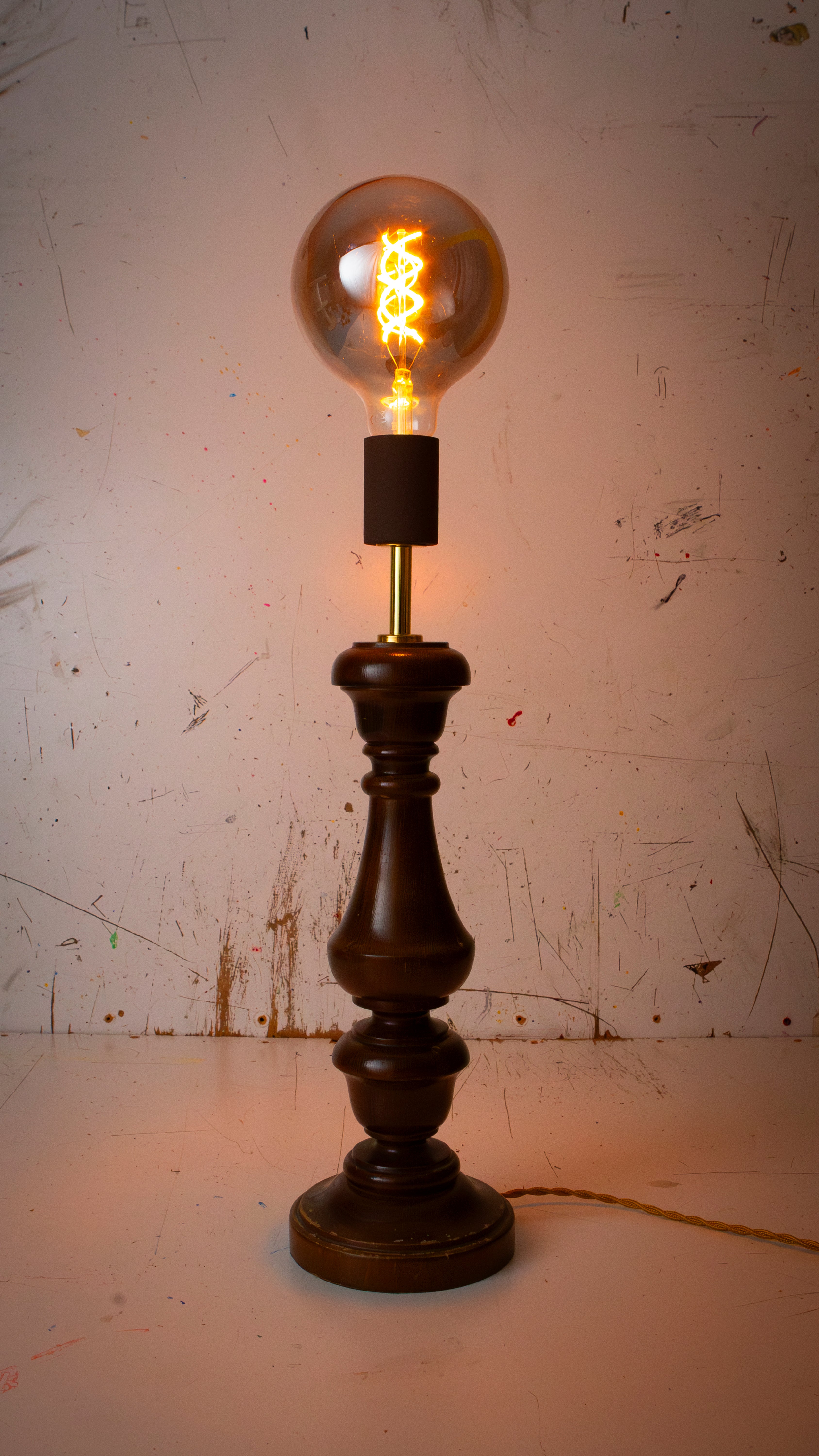 Vintage-style table lamp with a lit bulb on a textured white background