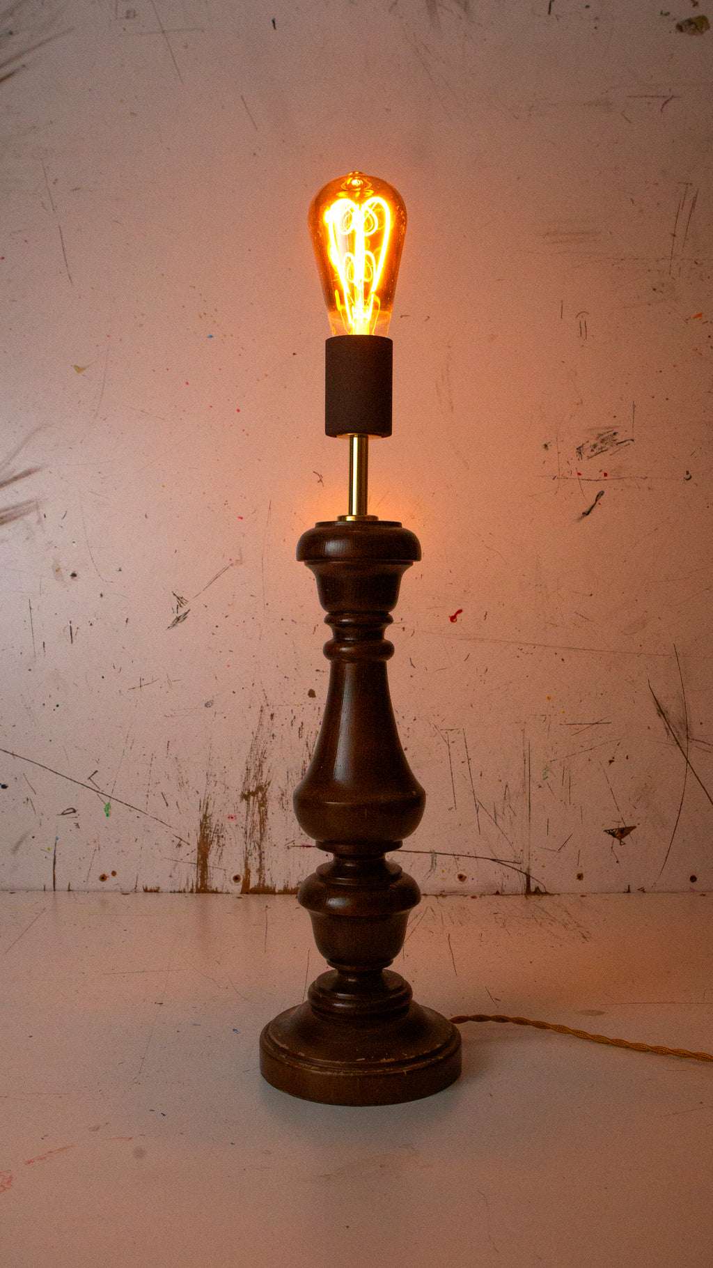 Vintage-style table lamp with a lit bulb on a textured surface