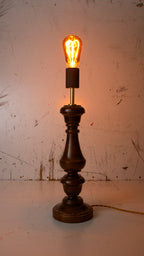 Vintage-style table lamp with a lit bulb on a textured surface