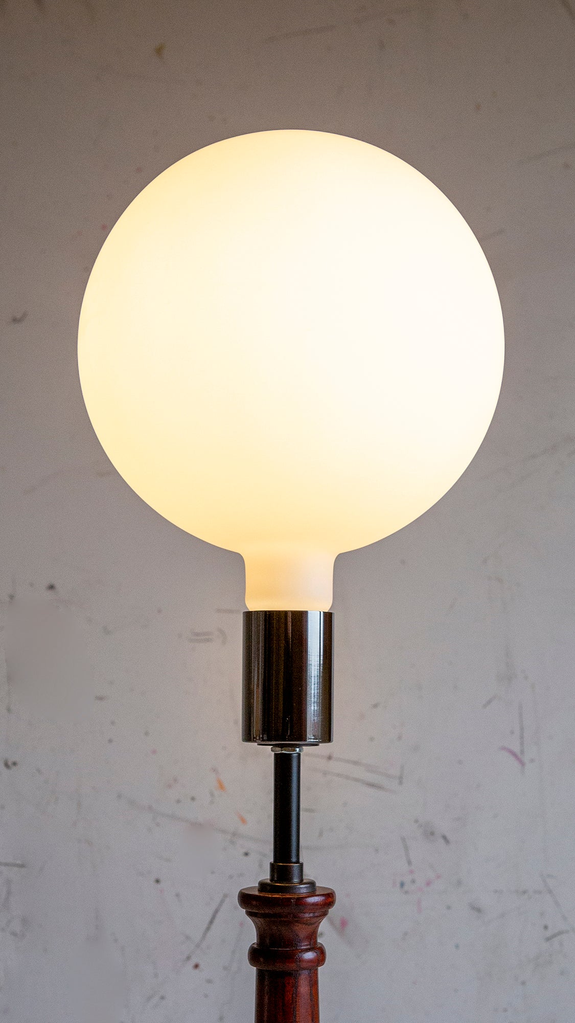 Light bulb on a stand against a plain background
